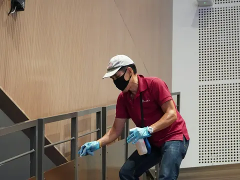 Reinigungskraft wischt ein Treppengeländer ab
