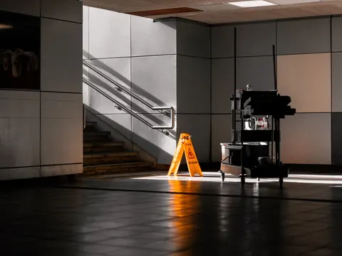 Eingangsbereich mit Treppe, Reinigungswagen und Warnschild