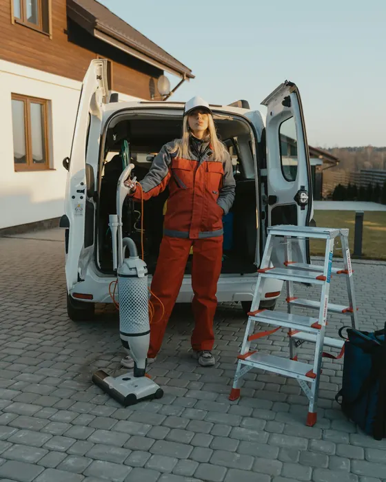 Servicekraft mit Reinigungsgeräten vor dem Einsatzfahrzeug