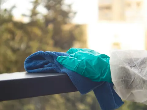 Handschuh und Tuch bei der Oberflächenreinigung