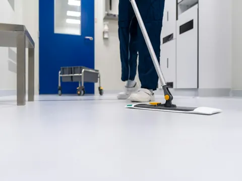 Reinigungskraft wischt den hellen Flur eines Gewerbeobjekts