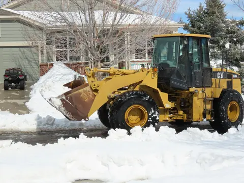 Radlader räumt Schnee vor einem Gebäude